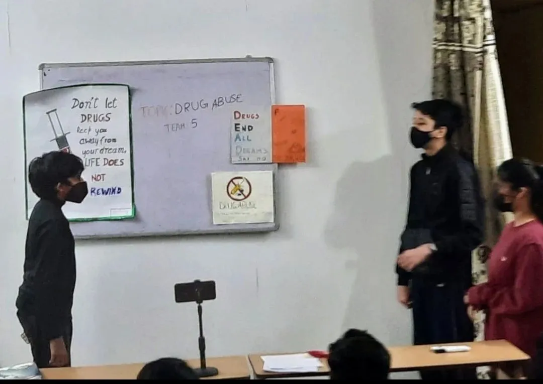 Students presenting their own posters on drug abuse at the whiteboard.