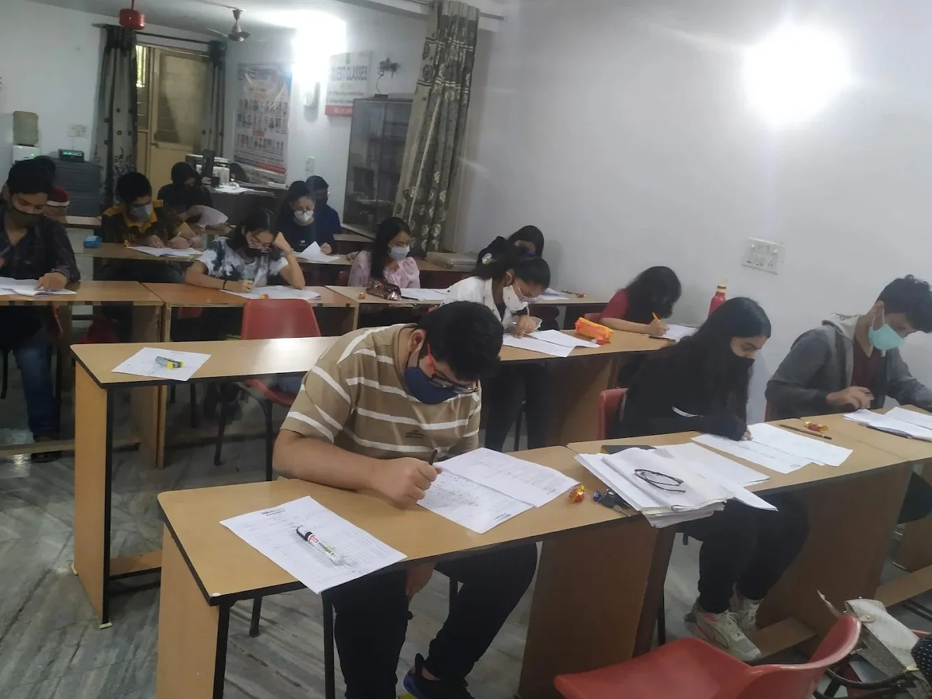 Students writing on answer sheets at their desks.