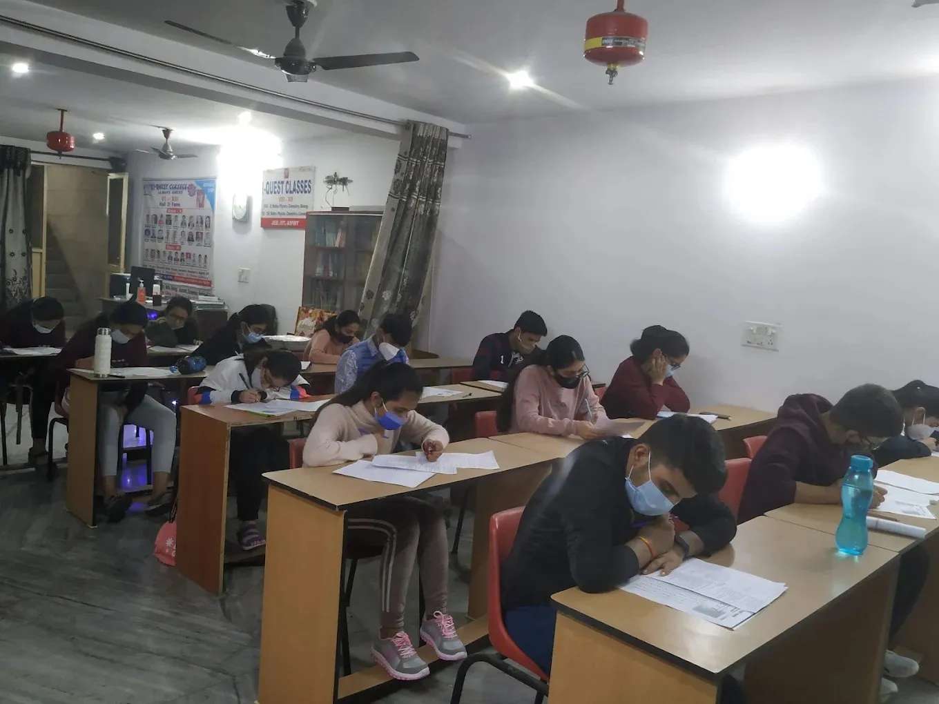 Students at their desks, with the I Quest Classes signboard on the wall behind them.