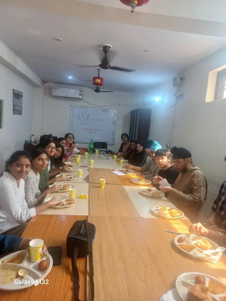 Students and teachers seated along a long table laid for lunch.