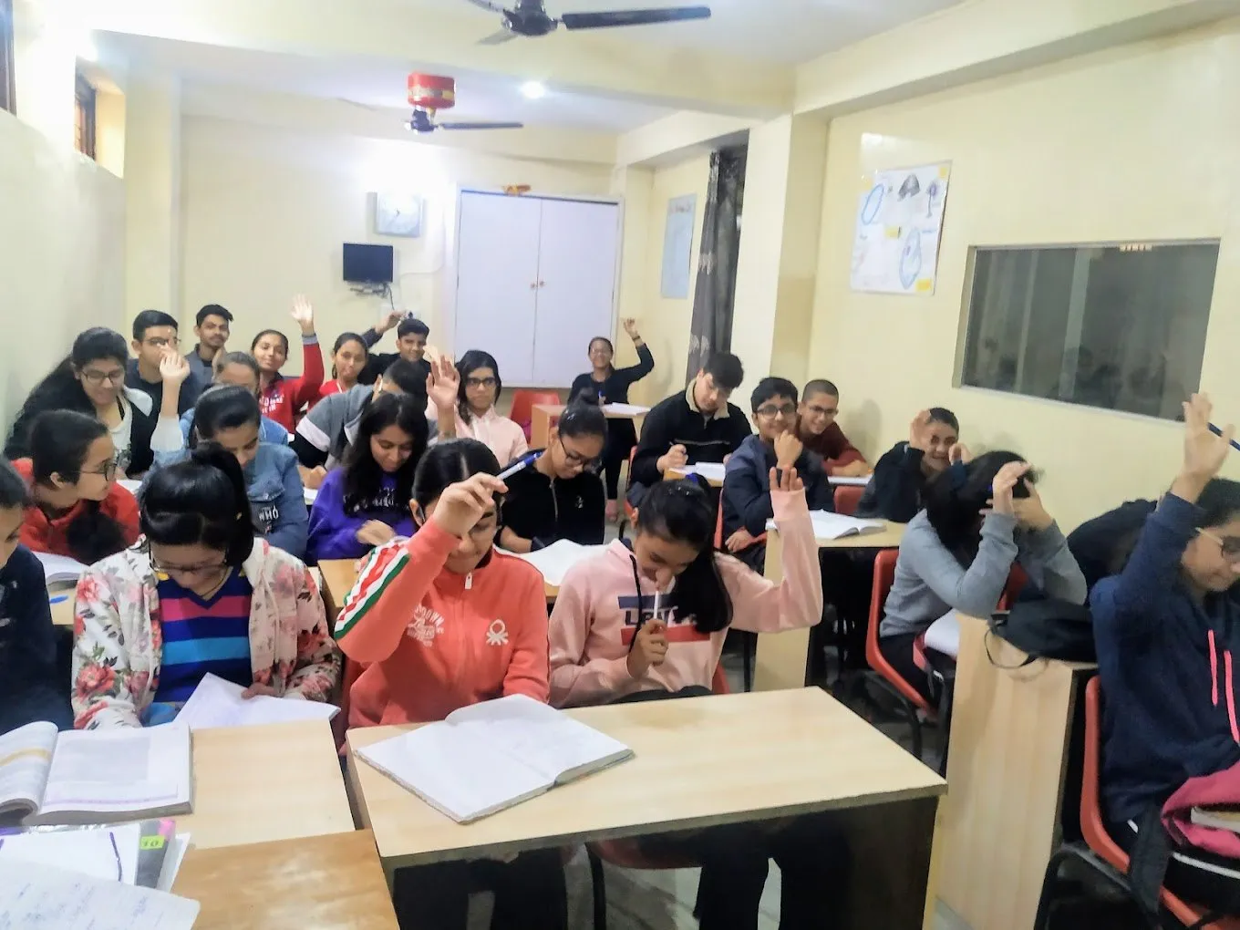 Students with their hands raised during a lesson.