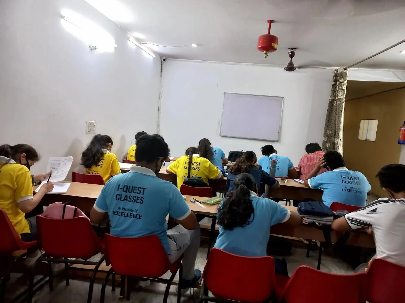 Students in school uniform working through a written test.